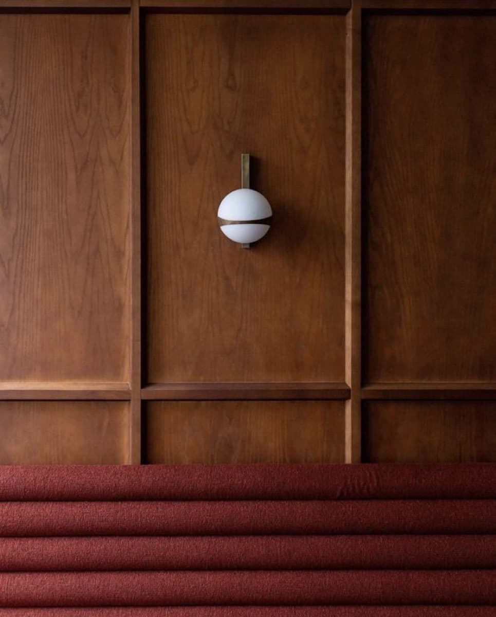 Boiserie de madera con un aplique esférico sobre un banco tapizado